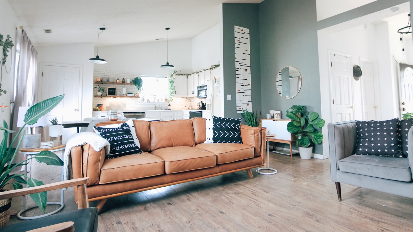 An industrial-style living space with exposed brick, black metal shelving, a leather sofa, and warm Edison bulb lighting